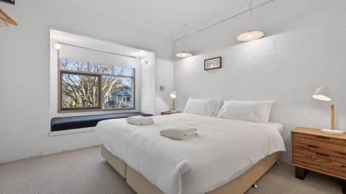 a white bedroom with a large bed and a window at Snowgums 10 in Dinner Plain