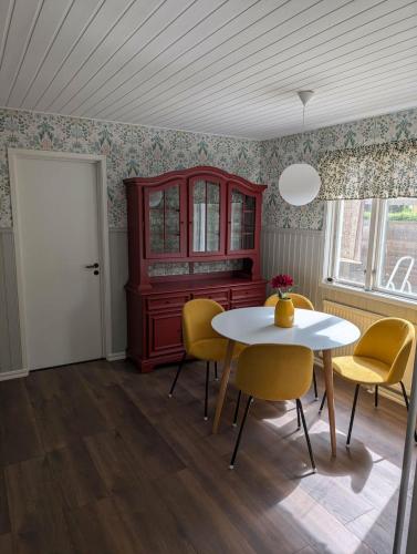 a dining room with a white table and yellow chairs at Villa Skäris in Falkenberg