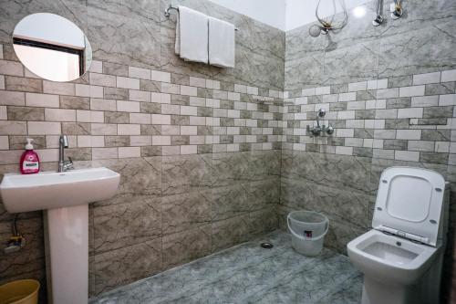 a bathroom with a sink and a toilet and a mirror at Gharonda Manor-A Home Beyond Home -Best Luxury Budget Stay Near ISBT in Dehradun