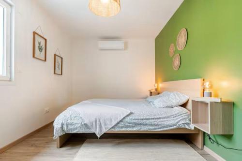 a bedroom with a bed and a green wall at Comme à la maison ! in Matour