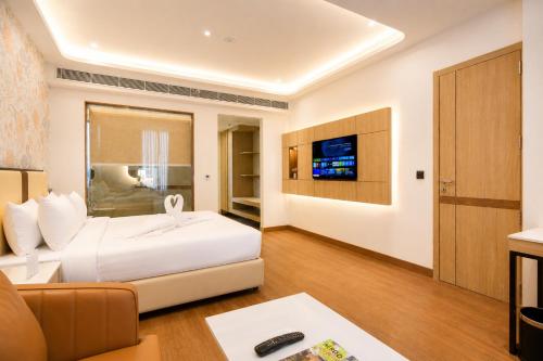 a hotel room with a bed and a tv at Pride Premier Greater Noida in Noida