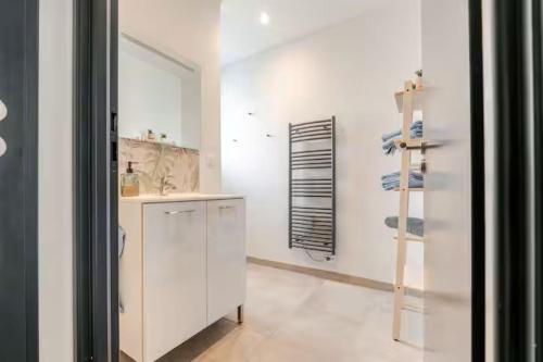 a white bathroom with a sink and a mirror at Comme à la maison ! in Matour