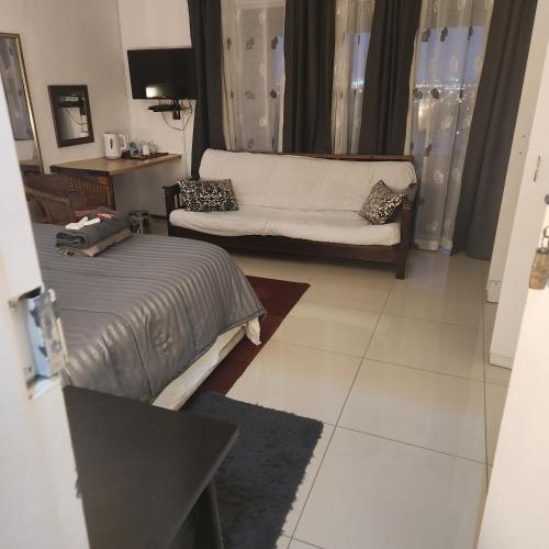a living room with a bed and a couch at Shirleys Place in Brackenfell