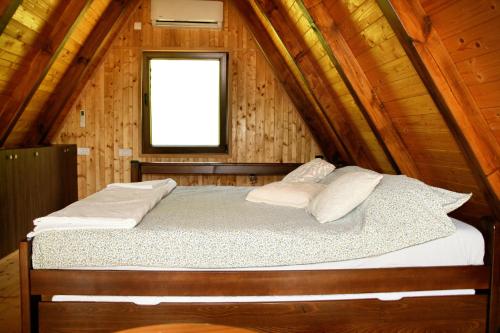 a bed in a wooden cabin with a window at A frame Svetosavska bajka in Lisice