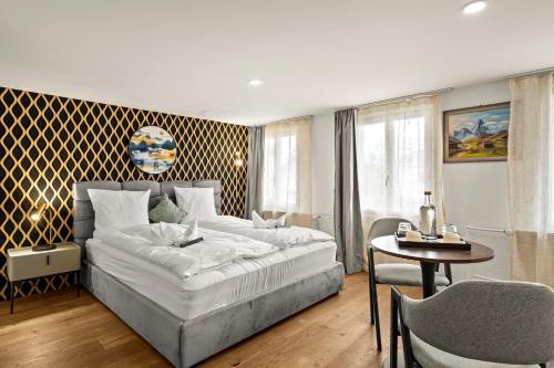 a bedroom with a large white bed and a table and chairs at BERG & BERG Hotel - Hellbühl Self-Check-in in Hellbühl