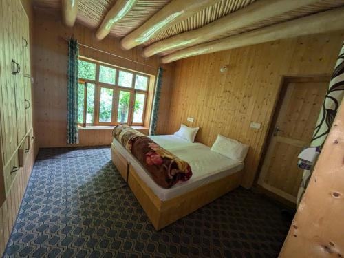 a bedroom with a bed in a wooden room at Turtuk Stream Side Home Stay in Turtuk
