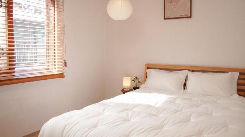 a white bed in a bedroom with a window at sinae stayG in Seoul