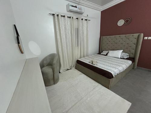 a small bedroom with a bed and a chair at Villa Djenné électricité 24h in Bamako