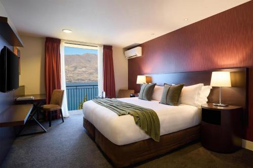 a hotel room with a large bed and a window at Rendezvous Heritage Hotel Queenstown in Queenstown