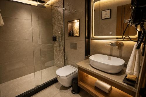 a bathroom with a toilet and a sink and a shower at Four Leaf Hotel Dehradun in Dehradun