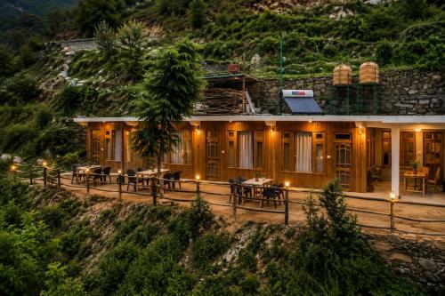 a hotel with tables and chairs in front of a mountain at KOKILARIVERSONGHomesaty in Banjār