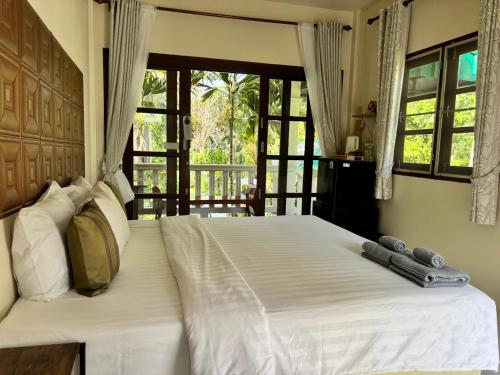 a bedroom with a large white bed and a window at Khaosok gallery & camp in Ban Khong Hua Kwang