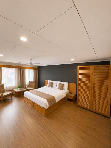 a bedroom with a large bed and a couch and chairs at Hotel Meridien Riverfront in Srinagar