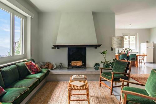 a living room with a green couch and a fireplace at Luxury Nature Retreat Villa Planchette in Lugano