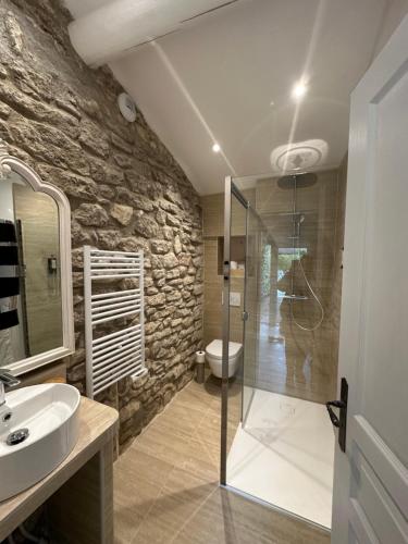 a bathroom with a glass shower and a sink at Mas des Romarins, The Originals Relais in Gordes