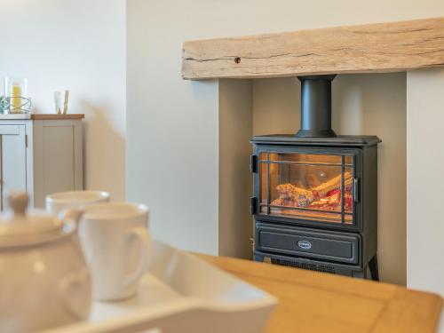 a wood stove in a kitchen with a table at Carr View Farm in Bamford