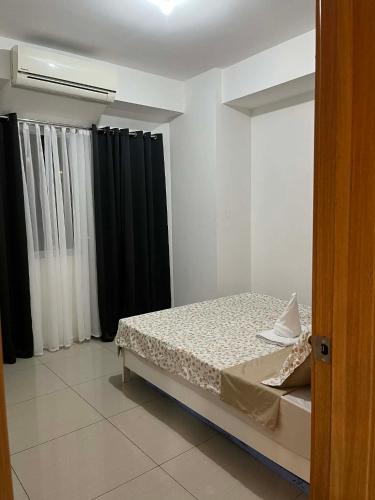 a bedroom with a bed and black curtains at Shell Staycation in Manila