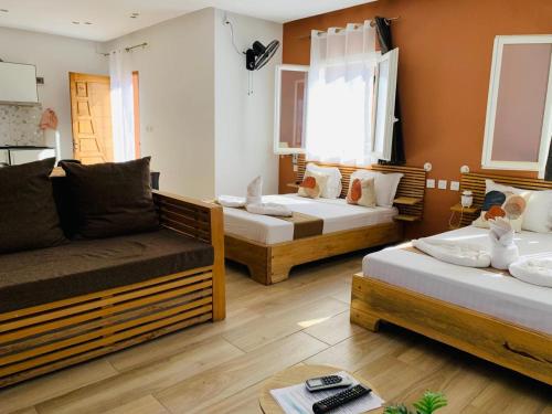 a living room with three beds and a couch at Odyssée Résidence in Mahajanga
