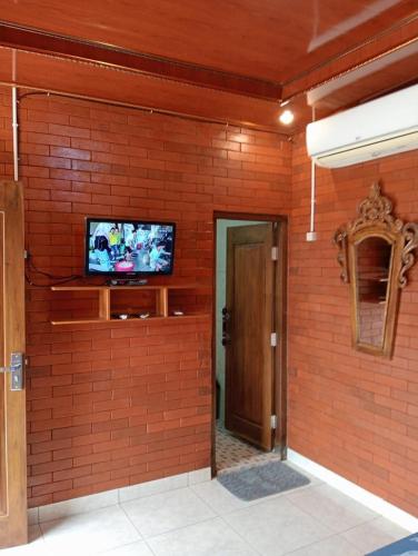 a room with a tv on a brick wall at Limasan Mbah Darmo in Tepus