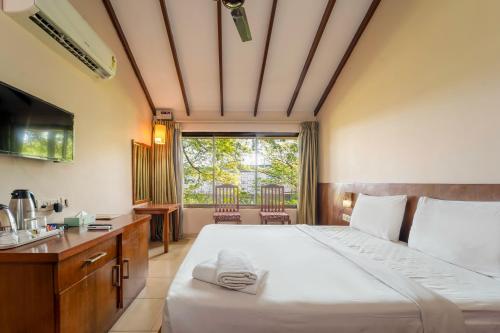 a bedroom with a bed and a sink and a window at Old Goa Residency in Old Goa