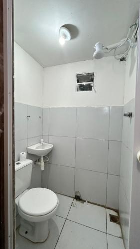 a white bathroom with a toilet and a sink at Fenomenall Kitnet in Campina Grande