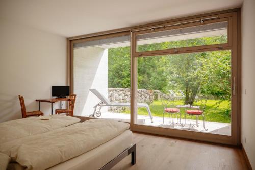 a bedroom with a large window with a view of a patio at Casa Martinelli, Boutique-Hotel in Maggia
