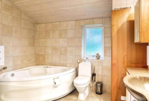 a bathroom with a tub and a toilet and a sink at Summerhouse On The Beach And With Ocean View in Yderby