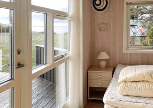a bedroom with a bed next to a window and a door at Summerhouse On The Beach And With Ocean View in Yderby