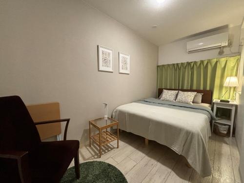 a small bedroom with a bed and a chair at Firmament Shimoshinjo in Osaka
