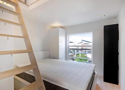 a small bedroom with a ladder and a bed at Exclusive Architect Designed Beach House in Karrebæksminde