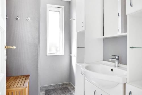 a white bathroom with a sink and a window at Summerhouse With Both Island Charm And Sea View in Holbæk