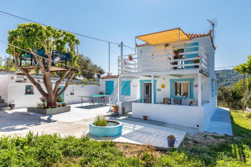 a white house with a tree in front of it at Pastalia Cottage in Skopelos Town