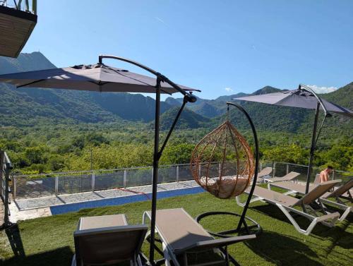 eine Terrasse mit Stühlen, einer Schaukel und einem Sonnenschirm in der Unterkunft Brioni in Virpazar