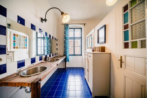 a bathroom with two sinks and a blue tile floor at Penzion Sborovna in Zbraslavice