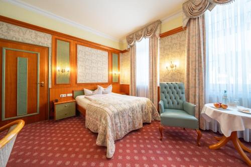 a hotel room with a bed and a chair and a table at Hotel Fürstenhof Bad Bertrich in Bad Bertrich