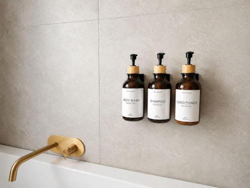 three bottles of wine on a wall above a bath tub at L'Aiglon- Piscine Naturelle Privatisable in Salvan