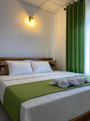 a bedroom with a large bed with green curtains at Mahagedara Villa Wilpattu in Nochchiyagama