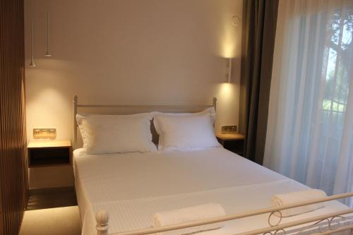 a bedroom with a bed with white pillows and a window at Thassos Studio Kai Lani in Potamiá