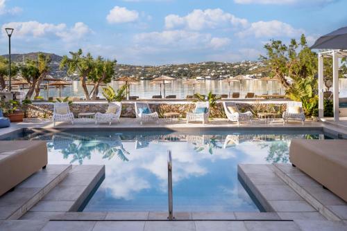 a pool at a hotel with chairs and trees at Alidian bay Suites Leros in Alinda
