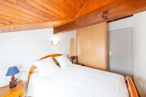 a bedroom with a white bed with a wooden ceiling at Escapade Landaise, Piscine in Capbreton