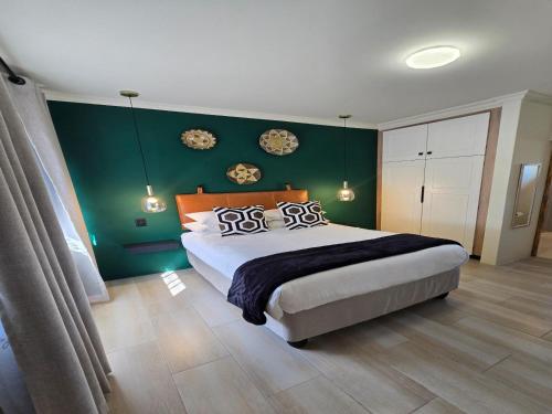 a bedroom with a large bed with a green wall at NiNETEEN28 Guesthouse in Pietermaritzburg