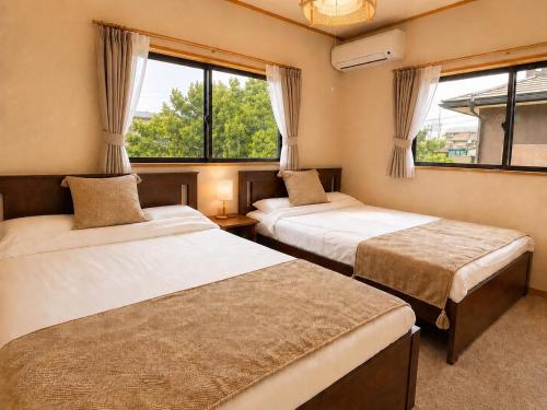 two beds in a room with two windows at Hamabun テラスでBBQ 湖まで徒歩5分 無料駐車場3台 in Takashima