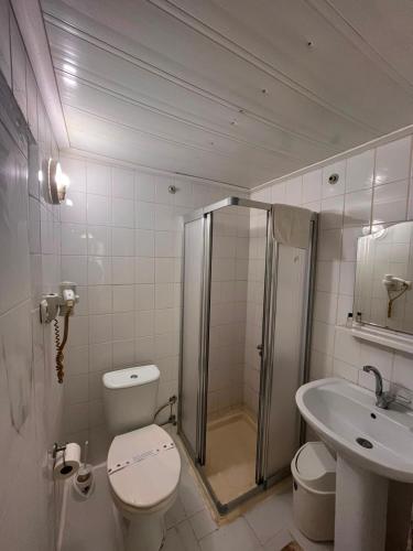a bathroom with a shower and a toilet and a sink at Kiraz Otel in Lapseki