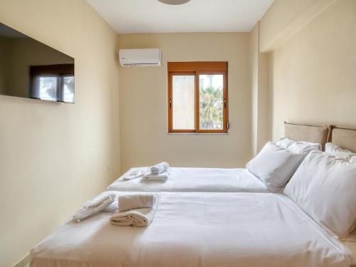 a bedroom with two beds with white sheets and a window at Azure Seaside Living in Kardamaina