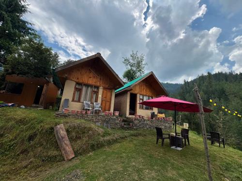 a house on a hill with a table and an umbrella at Shikhar cottage in Jibhi