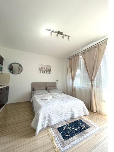a white bedroom with a bed and a window at Chic & Cozy Beige Studio in Bratislava