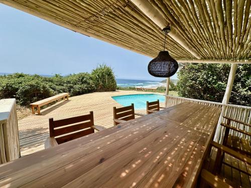 a wooden deck with a table and a swimming pool at Kangela 1 in Ponta Malangane