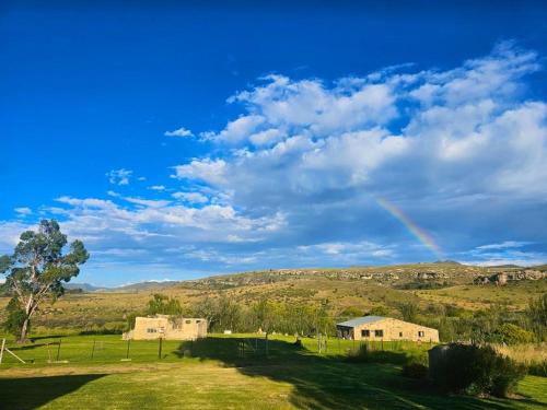 a rainbow in the sky over a field with a house at Clarossouw in Clarens
