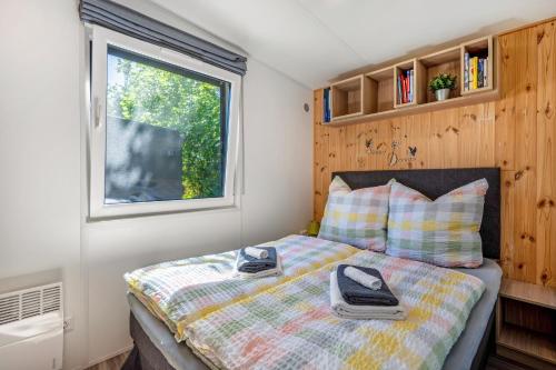 a bedroom with a bed with a comforter and a window at Tinyhaus Sankt Rupert Nummer 11 in Riedenburg