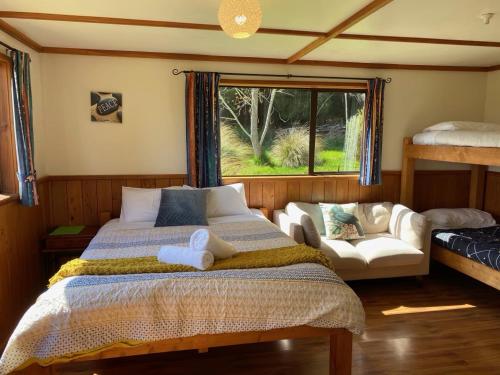 a bedroom with a bed and a couch and a window at Freestone Cabins in Manapouri